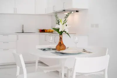 a white kitchen with a white table with a vase with flowers at Patong Tower Brand New 1-Bedroom , Near Beach in Patong Beach