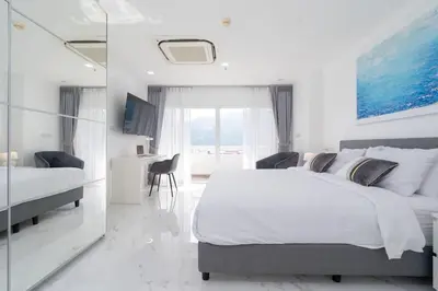 a white bedroom with a large bed and a desk at Patong Tower 1-Bedroom , 200 meters from the Beach in Patong Beach