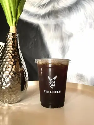 a cup of coffee and a vase on a table at Pinpoint Hotel Phuket in Ban Pak Lak