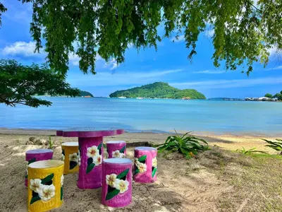 a table and stools on a beach with the ocean at Secret Place in Panwa Beach