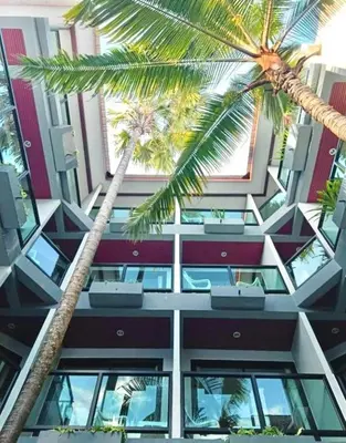 a building with two palm trees in front of it at Kata Noi Bay Inn in Kata Beach