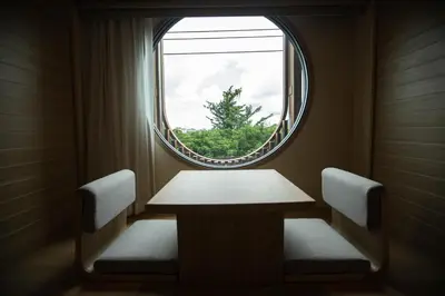 a table and two chairs in a room with a window at The Arch Phuket Hotel in Ban Ket Ho