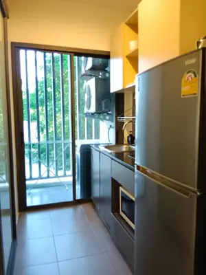 a kitchen with a stainless steel refrigerator and a balcony at Hill Myna Condotel by Bcare - One Bedroom in Ban Thalat Choeng Thale