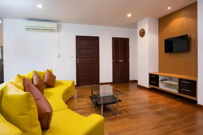 a living room with a yellow couch and a tv at iCheck inn Residences Patong in Patong Beach