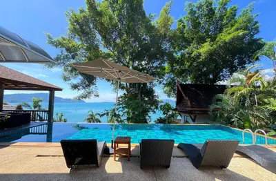a swimming pool with a table and an umbrella at Aoyon Beach, a 5-bedroom Thai-style villa with stunning sea views, 50 meters direct beach access, free maid, in Phuket Town