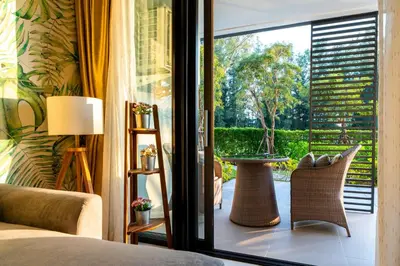 a bedroom with a door open to a patio with a table at Cassia 2 BR Sea View&Terrace apt by NLA in Bang Tao Beach