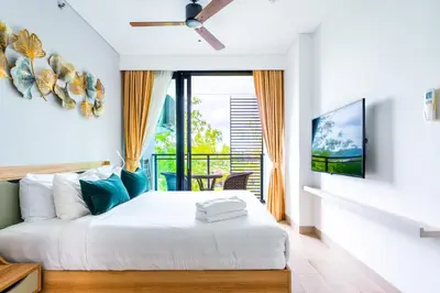 a bedroom with a white bed and a window at Cassia 2 BR Lake&Road View apt by NLA in Bang Tao Beach