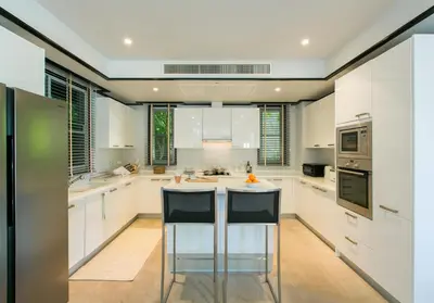 a kitchen with white cabinets and a island with bar stools at Katamanda Villa Mila A1 near Kata Beach in Kata Beach