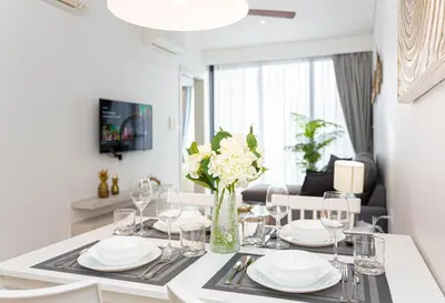 a dining room table with glasses and a vase of flowers at Cassia 1 BR Lake&Pool View apt by NLA in Bang Tao Beach