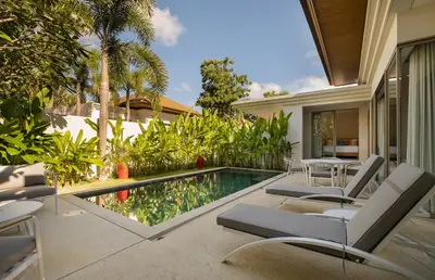 a swimming pool with chairs and a table next to a house at 3-Bedroom Pool Villa in Trichada Bangtao in Bang Tao Beach