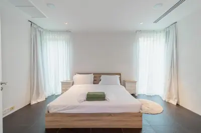 a bedroom with a large bed with white sheets and a rug at Cozy 5BR Villa Stunning SeaViews in Kamala Beach