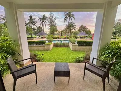 a porch with two chairs and a table and a pool at Golf View, Allamanda 3 Apartment in Ban Mut Dok Khao