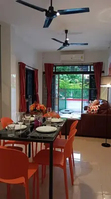 a dining room with a table and chairs and a room with a couch at Naka Tangerine Holiday Home by Bcare in Ban Rangeng