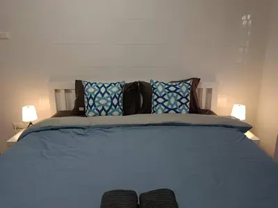 a bedroom with a blue bed with two lamps at Naka Tangerine Holiday Home by Bcare in Ban Rangeng