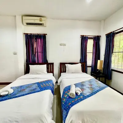 two beds in a room with purple curtains at Chamil House (ชามิล เฮ้าส์) in Ban Ko En