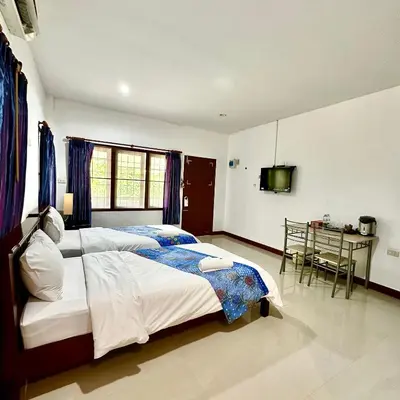 a bedroom with a bed and a table in it at Chamil House (ชามิล เฮ้าส์) in Ban Ko En