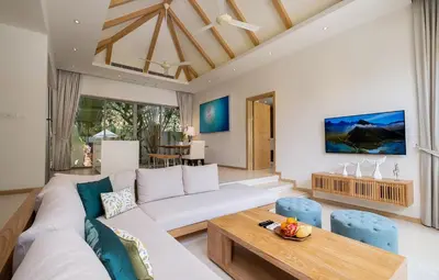 a living room with a white couch and a wooden table at 3-Bedroom Pool Villa in Trichada Sky at Bangtao in Bang Tao Beach