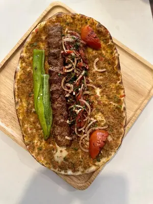 a pizza with meat and vegetables on a cutting board at Istanbul Boutique Hotel in Patong Beach