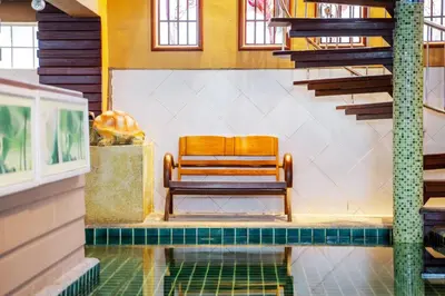 a wooden bench sitting in a room with a pool at Orchid Pool Villa - SHA Extra Plus - indoor Warm pool in Phuket Town