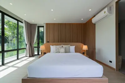 a bedroom with a large white bed and large windows at Aya Residence Garden View in Ban Ket Ho