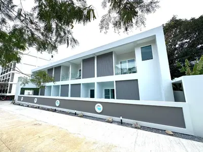 a white building with trees in front of it at Kata Place Villa in Kata Beach