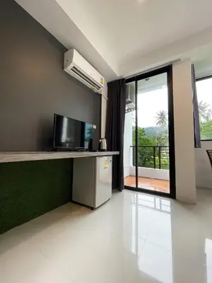 a room with a kitchen with a television and a balcony at Kefir Phuket in Kamala Beach