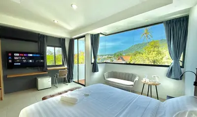 a bedroom with a bed and a large window at Kefir Phuket in Kamala Beach