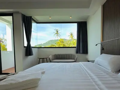 a bedroom with a bed and a large window at Kefir Phuket in Kamala Beach