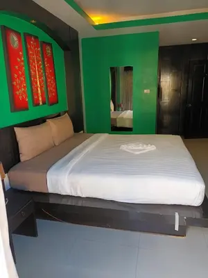 a bedroom with a large bed with a green wall at New Lavender Hotel Patong in Patong Beach