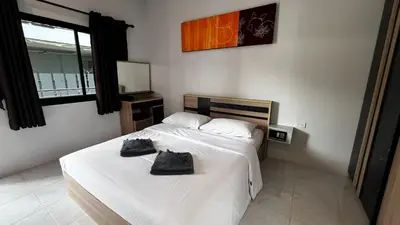 a bedroom with a bed with two black bags on it at M&N Guesthouse Kata in Kata Beach
