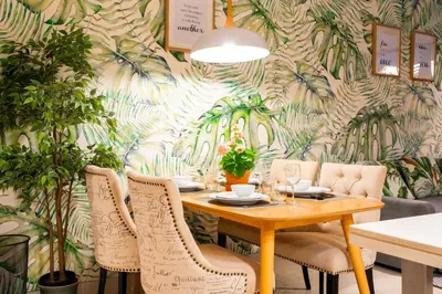 a dining room with a table with chairs and a tropical wallpaper at Cassia Residences by NLA in Bang Tao Beach