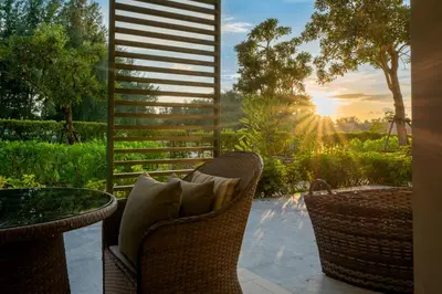 a patio with wicker chairs and a table and the sunset at Cassia Residences by NLA in Bang Tao Beach