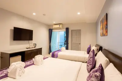 a hotel room with two beds and a flat screen tv at The Great @Patong Hotel in Patong Beach