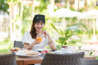 a woman sitting at a table with a glass of orange juice at Touch Sea Boutique Hotel&Bistro in Karon Beach