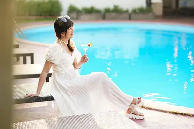 a woman in a white dress sitting next to a pool at Touch Sea Boutique Hotel&Bistro in Karon Beach