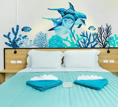 a bedroom with a bed with a dolphin mural on the wall at Touch Sea Boutique Hotel&Bistro in Karon Beach