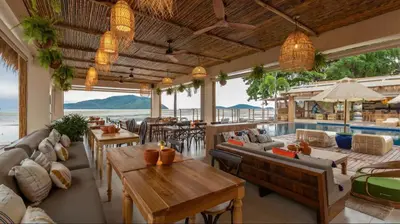 a restaurant with couches and tables and a pool at Poppy Beachfront Residence in Rawai Beach