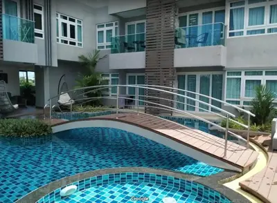 a swimming pool with a walkway in front of a building at Calypso Gardens 1 Bedroom Condo In Nai Harn in Rawai Beach