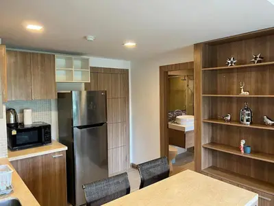 a kitchen with a stainless steel refrigerator and wooden cabinets at Calypso Gardens 1 Bedroom Condo In Nai Harn in Rawai Beach