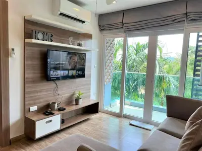 a living room with a flat screen tv on a wall at Calypso Gardens 1 Bedroom Condo In Nai Harn in Rawai Beach
