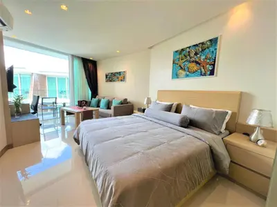 a bedroom with a large bed and a living room at Maroon Studio at the beachfront in Rawai Beach