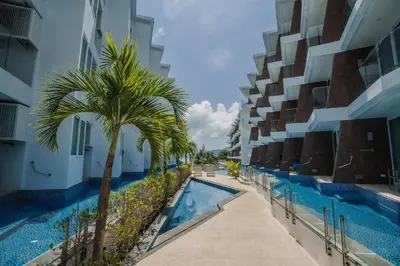 an image of a swimming pool in a building with a palm tree at Maroon Studio at the beachfront in Rawai Beach