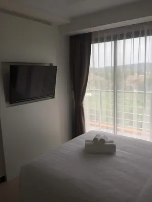 a bedroom with a bed and a large window at Mai Khao Beach Apartments in Mai Khao Beach