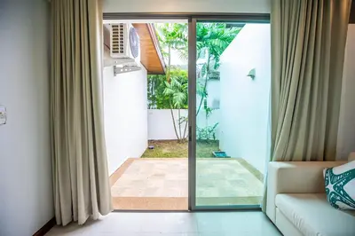 a living room with a couch and a sliding glass door at Phuket Boutique Pool Villa-80 in Rawai Beach