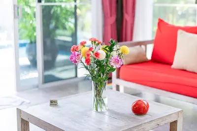 a vase of flowers on a table in a living room at VILLA FLORA - North Phuket, Naiyang Beach area in Nai Yang Beach