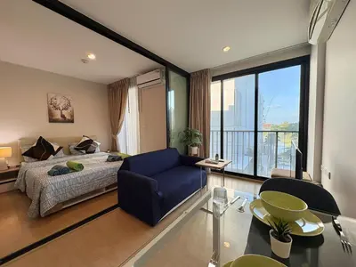a bedroom with a blue chair and a bed and a window at Zcape X2 Condos in Bangtao in Bang Tao Beach