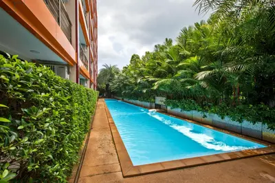 a swimming pool in front of a building with trees at 1 bdr Apartment Naiharn Beach Condo by CapitalPro in Phuket Town