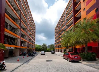 a red car parked in a parking lot next to buildings at 1 bdr Apartment Naiharn Beach Condo by CapitalPro in Phuket Town
