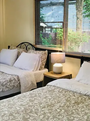 two beds in a room with a window and a table at Master Bedroom with private bathroom and kitchen in Phuket Town