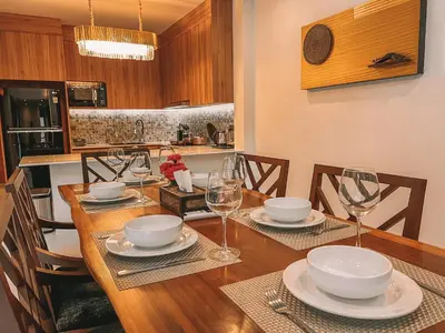 a kitchen with a wooden table with plates and wine glasses at Le Villa Residence in Phuket Town